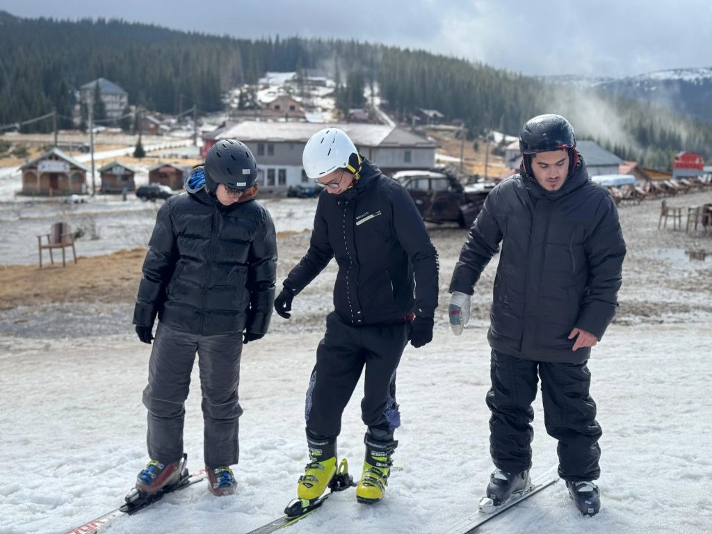 Instructor si studenti cu dizabiltiati pe schiuri